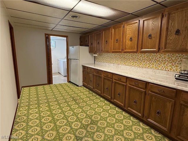 213 Stardust Dr, Wintersville, OH 43953 - kitchen featuring freestanding refrigerator, light countertops, a paneled ceiling, tasteful backsplash, and washing machine and clothes dryer