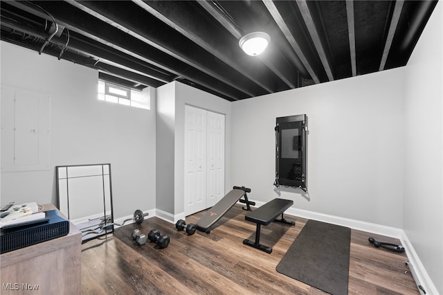 exercise area featuring electric panel, wood finished floors, and baseboards