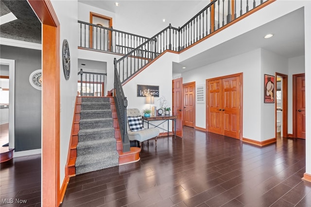 foyer entrance featuring recessed lighting, stairway, a high ceiling, wood finished floors, and baseboards