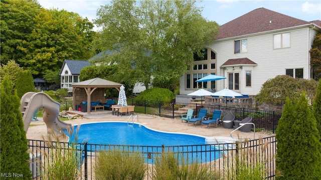 view of pool featuring a gazebo, a water slide, a patio, and fence