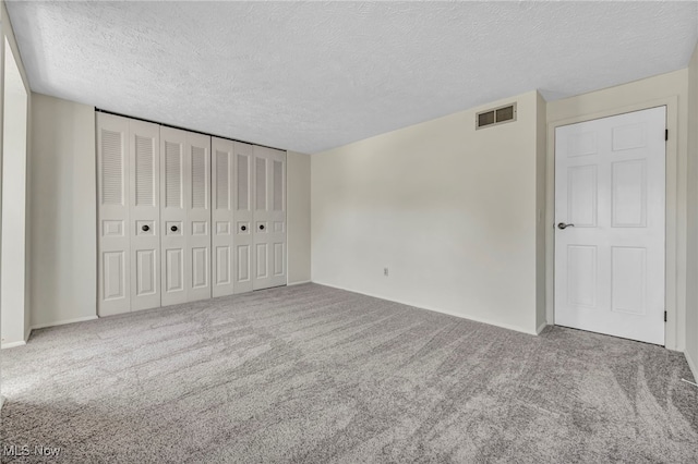 unfurnished bedroom with a textured ceiling, baseboards, visible vents, a closet, and carpet floors