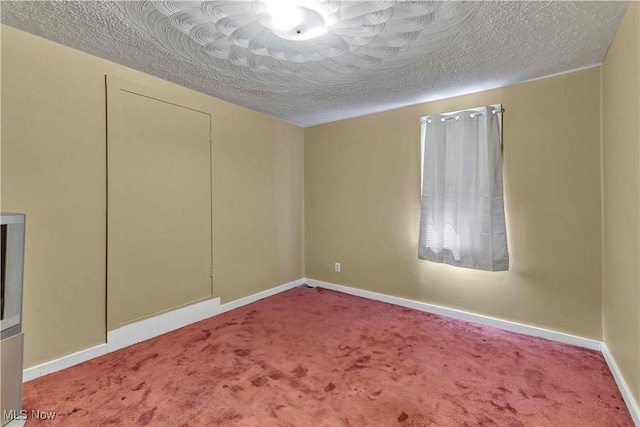 carpeted spare room featuring baseboards and a textured ceiling