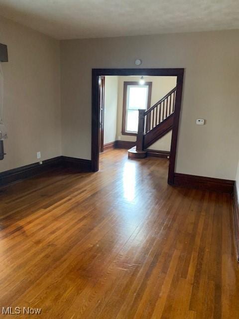 spare room with wood finished floors, baseboards, and stairway