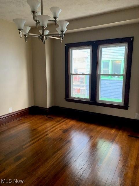 empty room featuring dark wood finished floors and a chandelier