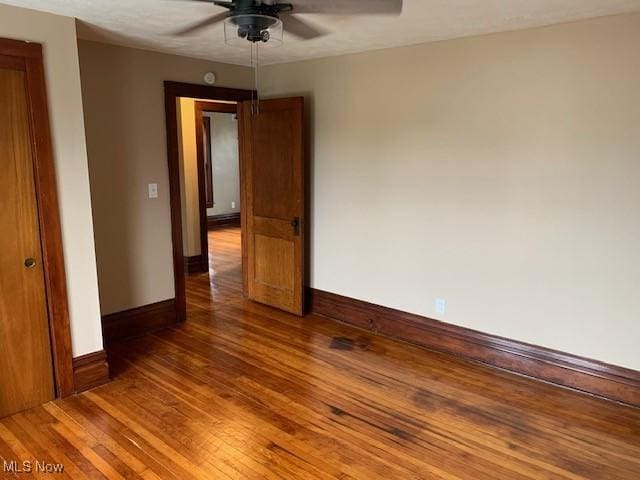 unfurnished room featuring wood finished floors, a ceiling fan, and baseboards