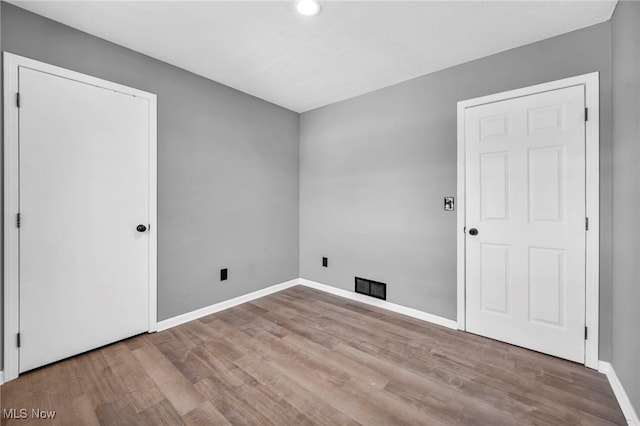 unfurnished room with baseboards, wood finished floors, visible vents, and recessed lighting