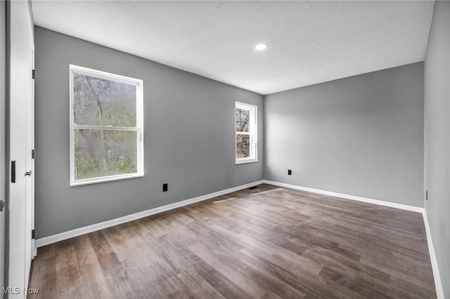 empty room featuring recessed lighting, wood finished floors, a textured ceiling, and baseboards