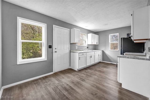 kitchen featuring light countertops, freestanding refrigerator, dark wood-style flooring, baseboards, and white cabinetry