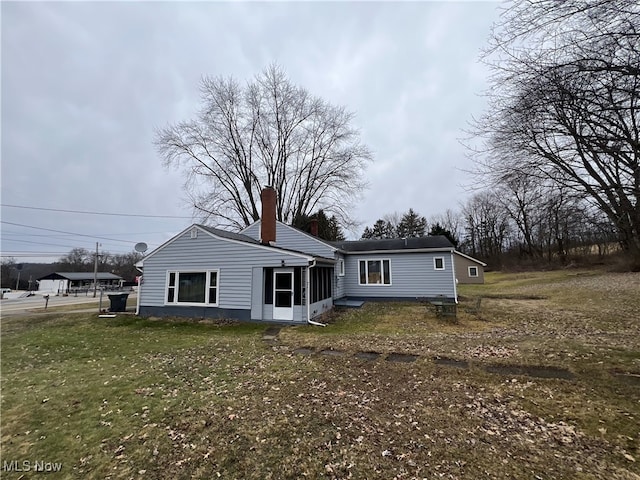 back of house featuring a chimney, a sunroom, and a yard
