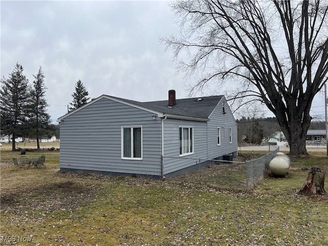 view of side of home featuring a chimney and fence