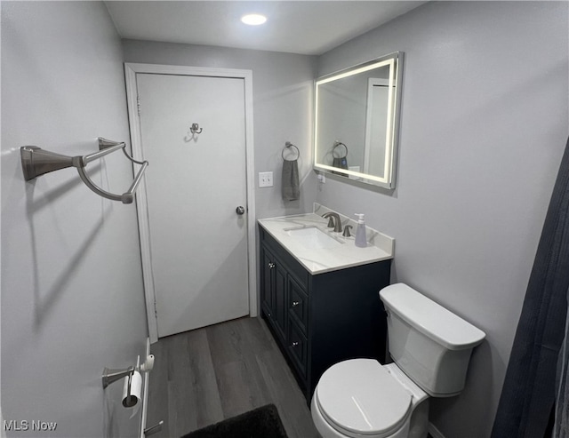 bathroom featuring wood finished floors, toilet, and vanity