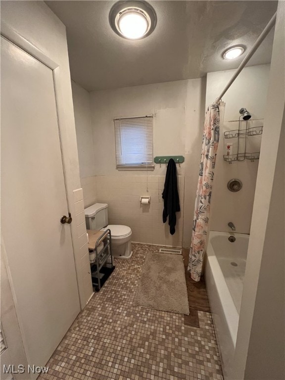 bathroom with shower / tub combo with curtain, toilet, and tile patterned floors