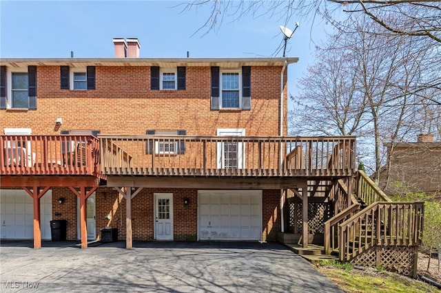 1332 Springbrook Dr, Mansfield, OH 44906 - rear view of property featuring brick siding, a wooden deck, driveway, a chimney, and a garage
