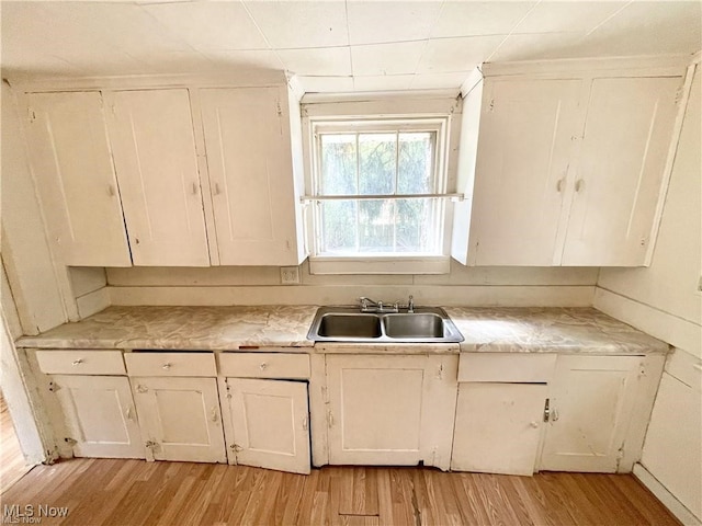 974 Madison Ave, Alliance, OH 44601 - kitchen featuring white cabinets, a sink, light countertops, and light wood-style flooring