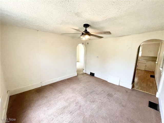 974 Madison Ave, Alliance, OH 44601 - carpeted empty room with a ceiling fan, a textured ceiling, arched walkways, baseboards, and visible vents