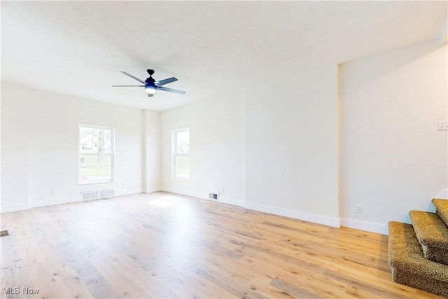 unfurnished room featuring baseboards, light wood-style flooring, visible vents, and stairs