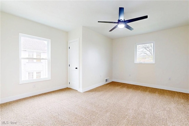 carpeted empty room with visible vents, a ceiling fan, and baseboards