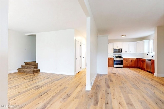 kitchen featuring open floor plan, white cabinetry, appliances with stainless steel finishes, and light wood finished floors