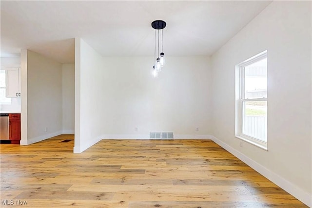 unfurnished dining area featuring light wood-type flooring, visible vents, and baseboards