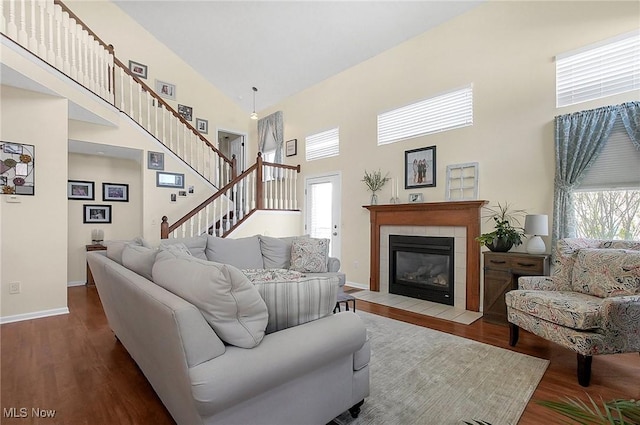 living area with a fireplace, wood finished floors, a high ceiling, and baseboards