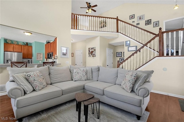living room featuring high vaulted ceiling, stairway, a ceiling fan, wood finished floors, and baseboards