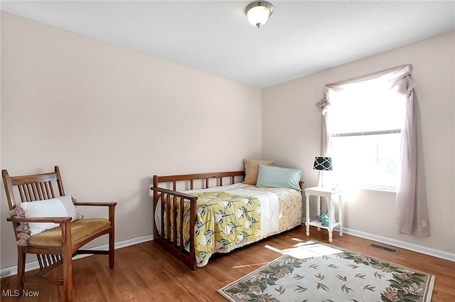 bedroom featuring baseboards, wood finished floors, and visible vents
