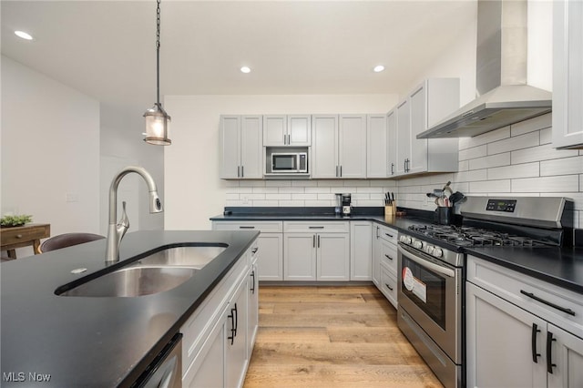 1804 28th St, Vienna, WV 26105 - kitchen featuring dark countertops, a sink, light wood-type flooring, wall chimney exhaust hood, and appliances with stainless steel finishes