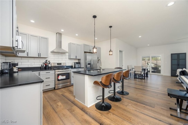 1804 28th St, Vienna, WV 26105 - kitchen featuring wall chimney range hood, dark countertops, a sink, a breakfast bar, and stainless steel appliances
