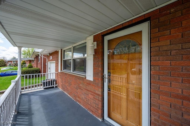 entrance to property with covered porch and brick siding