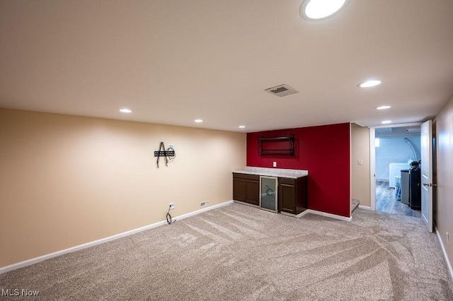 bar featuring bar area, baseboards, visible vents, and light colored carpet