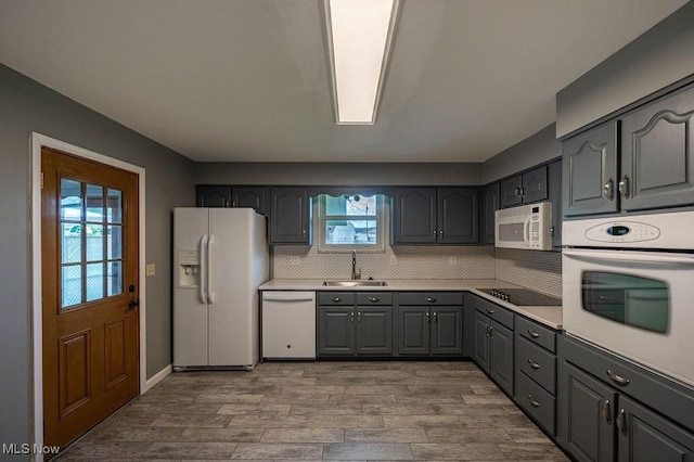kitchen with a sink, decorative backsplash, white appliances, gray cabinets, and light countertops