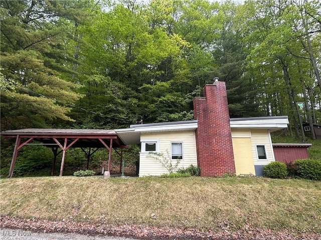 31713 Tappan Hills Rd, Tippecanoe, OH 44699 - view of property exterior featuring a chimney, a lawn, and a carport