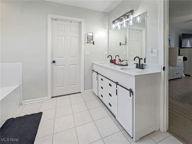 bathroom with tile patterned floors, baseboards, double vanity, and a sink