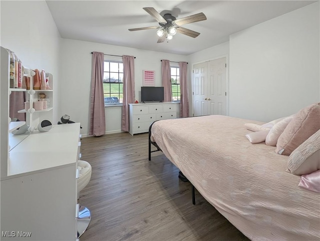 bedroom with a closet, ceiling fan, wood finished floors, and baseboards