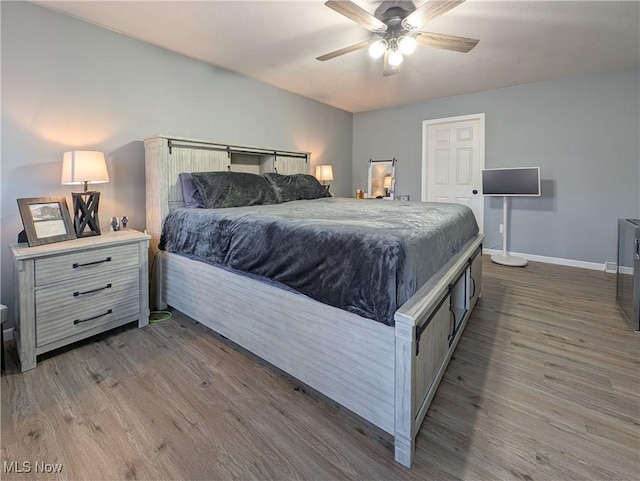 bedroom featuring ceiling fan, wood finished floors, and baseboards