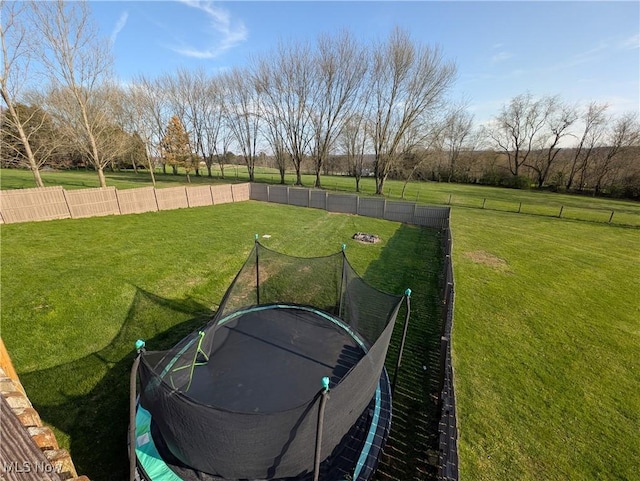 view of yard featuring a trampoline and fence
