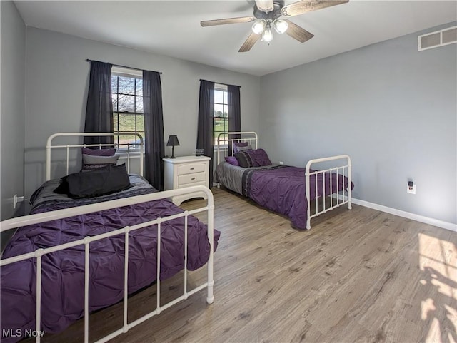 bedroom featuring visible vents, light wood-type flooring, a ceiling fan, and baseboards