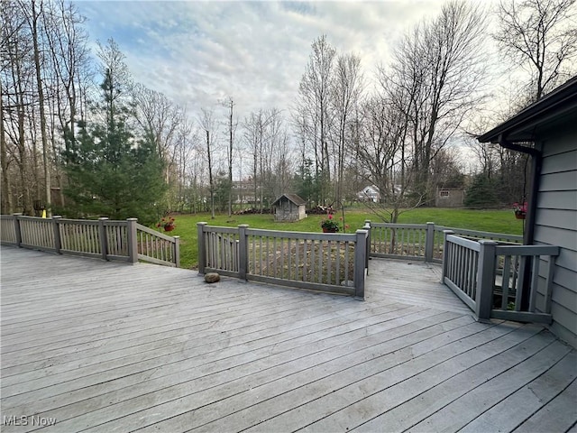 wooden deck with a lawn, an outdoor structure, and a storage unit