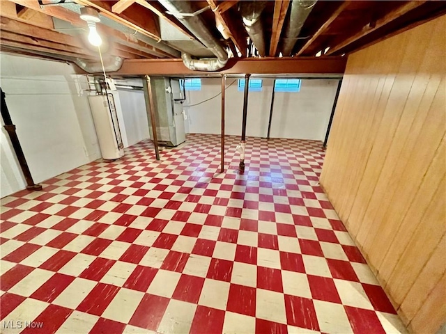 basement with water heater, tile patterned floors, and wooden walls