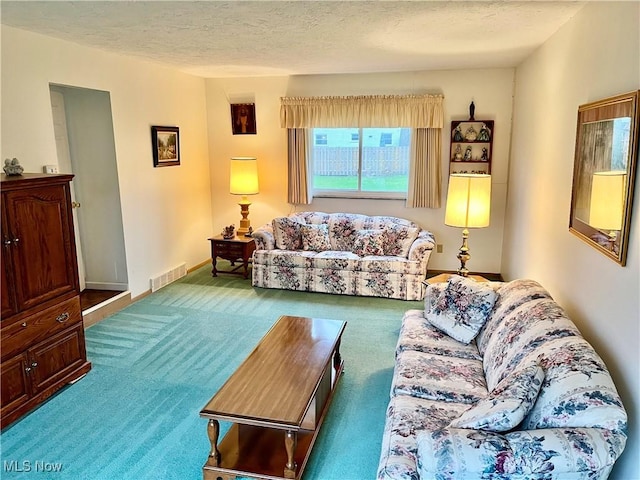 living room with a textured ceiling, carpet, and visible vents