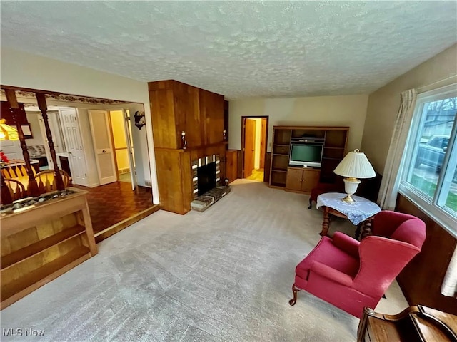 carpeted living area featuring a fireplace and a textured ceiling