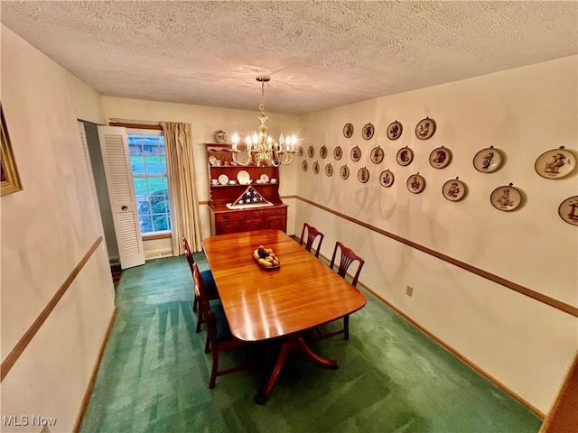 dining room featuring dark carpet, a textured ceiling, baseboards, and a notable chandelier