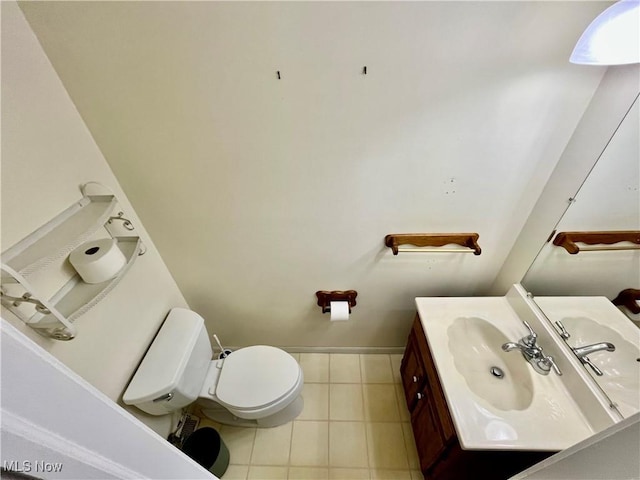 half bath featuring tile patterned floors, baseboards, vanity, and toilet