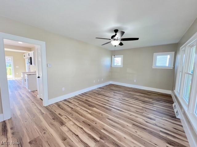 spare room featuring light wood finished floors, baseboards, and a ceiling fan