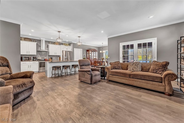 living area with recessed lighting, light wood-style floors, and an inviting chandelier