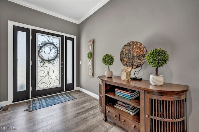 entryway with wood finished floors, baseboards, and ornamental molding