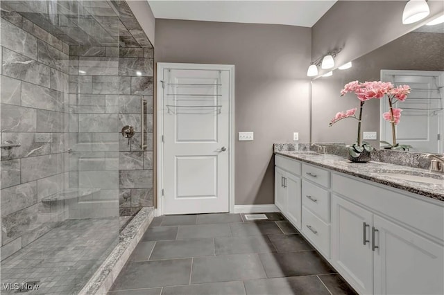 bathroom with baseboards, a sink, double vanity, and tiled shower