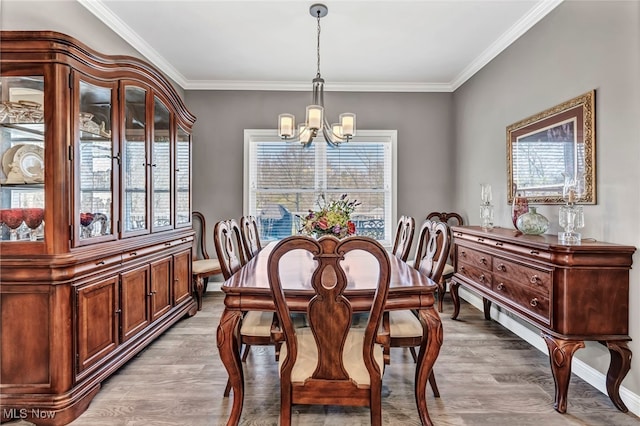 dining area with an inviting chandelier, ornamental molding, wood finished floors, and baseboards
