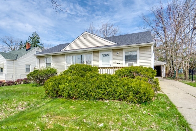 bungalow-style house with fence, a shingled roof, a front yard, and a garage