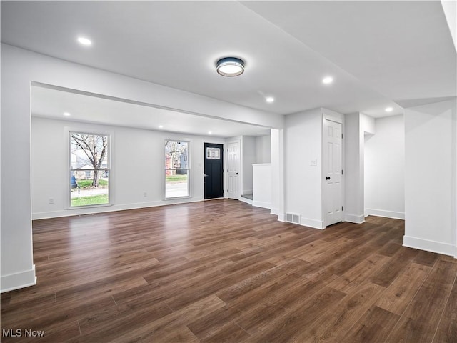 unfurnished living room with baseboards, recessed lighting, and dark wood finished floors